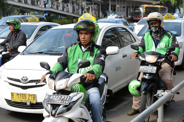 Go-Jek Indonesia Pt. motorcycle taxi riders drive along a street in Jakarta, Indonesia on Monday, March 21, 2016. The Jakarta-based startup has already become a household name in its home country. The startup's app has been downloaded more than 11 million times and it has more than 200,000 motorbikes. Its name is a play on ojek, the Indonesian word for the motorcycle taxis that crisscross Southeast Asia's most populous nation. Photographer: Dimas Ardian/Bloomberg