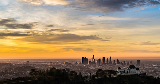Aerial view of the downtown Los Angeles skyline and the Griffith Park Observatory just after sunrise during the golden hour