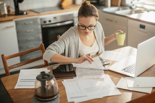 Close up of a young woman sitting in kitchen and  going through her financials