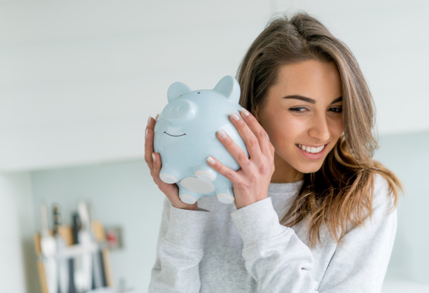Happy young woman saving money in a piggybank - home finances concepts